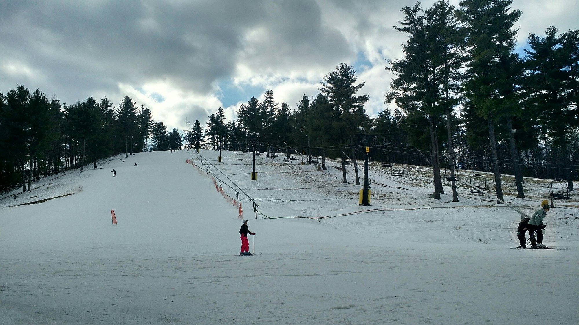 A lively winter sports scene at Nashoba Valley Ski Area in Westford MA with a skier in motion and visible ski lift amidst a bustling ski resort.