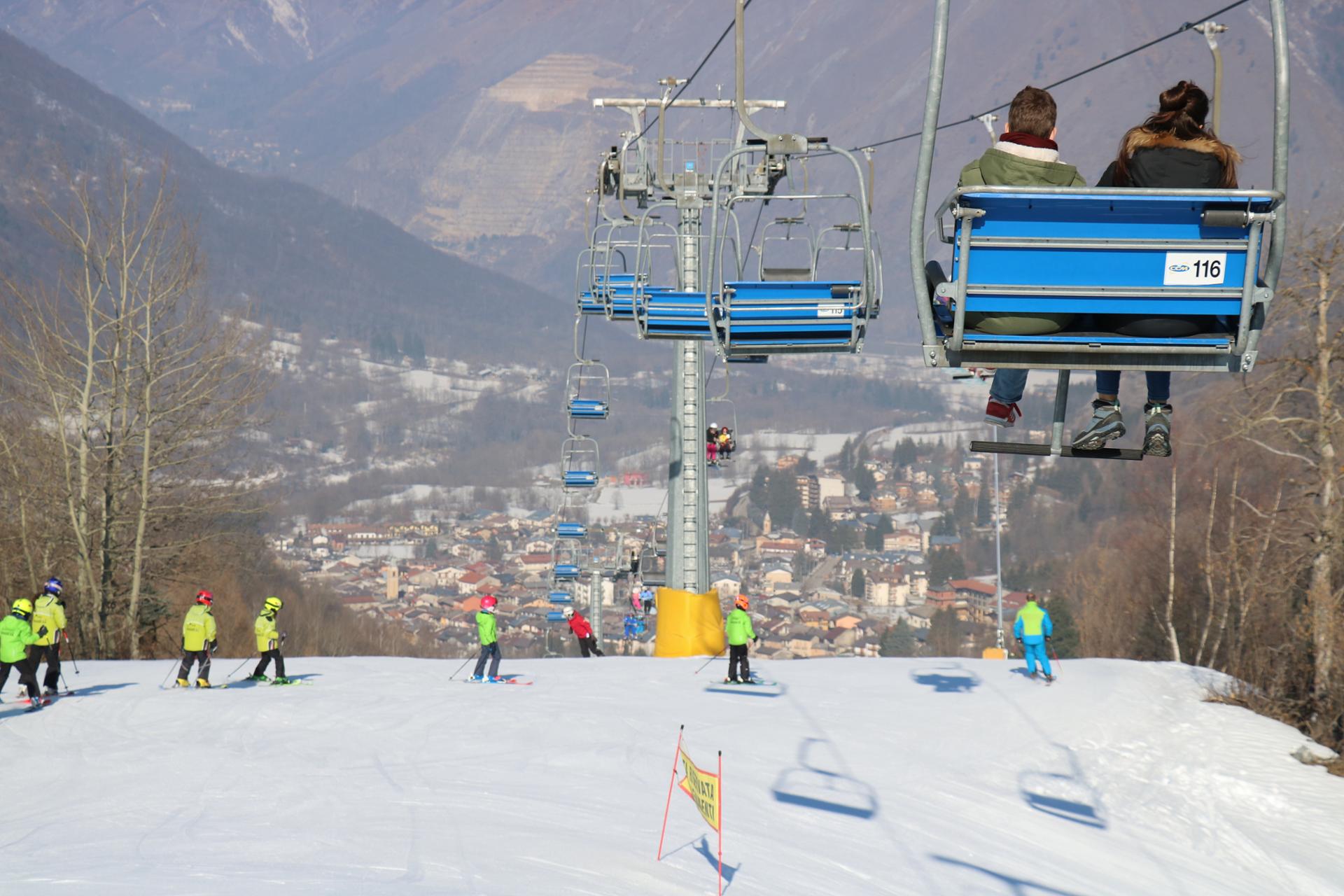 Scenic view of Entracque in Piedmont Italy featuring a ski lift and thriving winter sports at a ski resort. Skiers can be seen in action near a charming chalet.