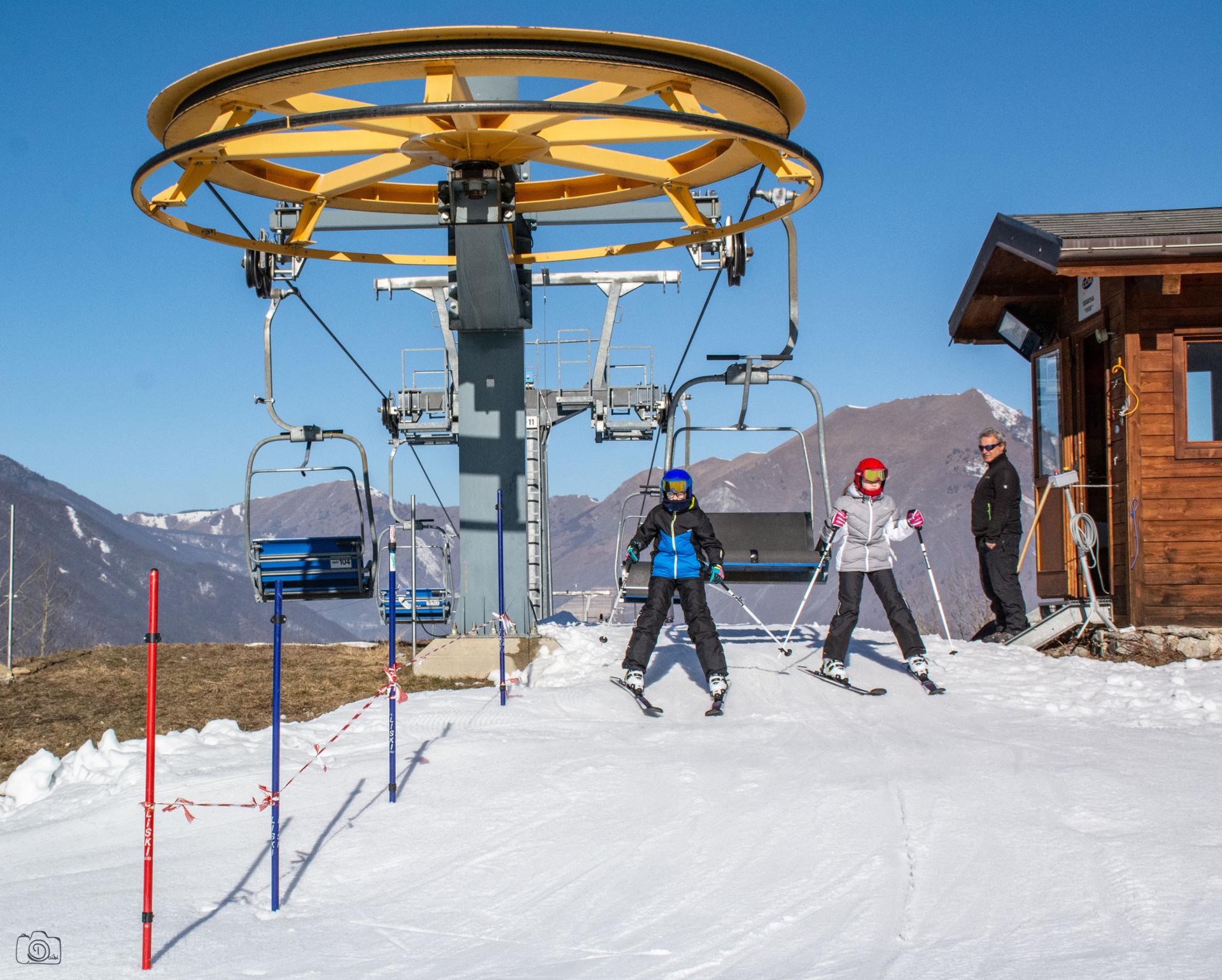 A winter scene at Entracque ski resort in Piedmont, Italy, featuring a ski lift and a skier with a chalet in the background.