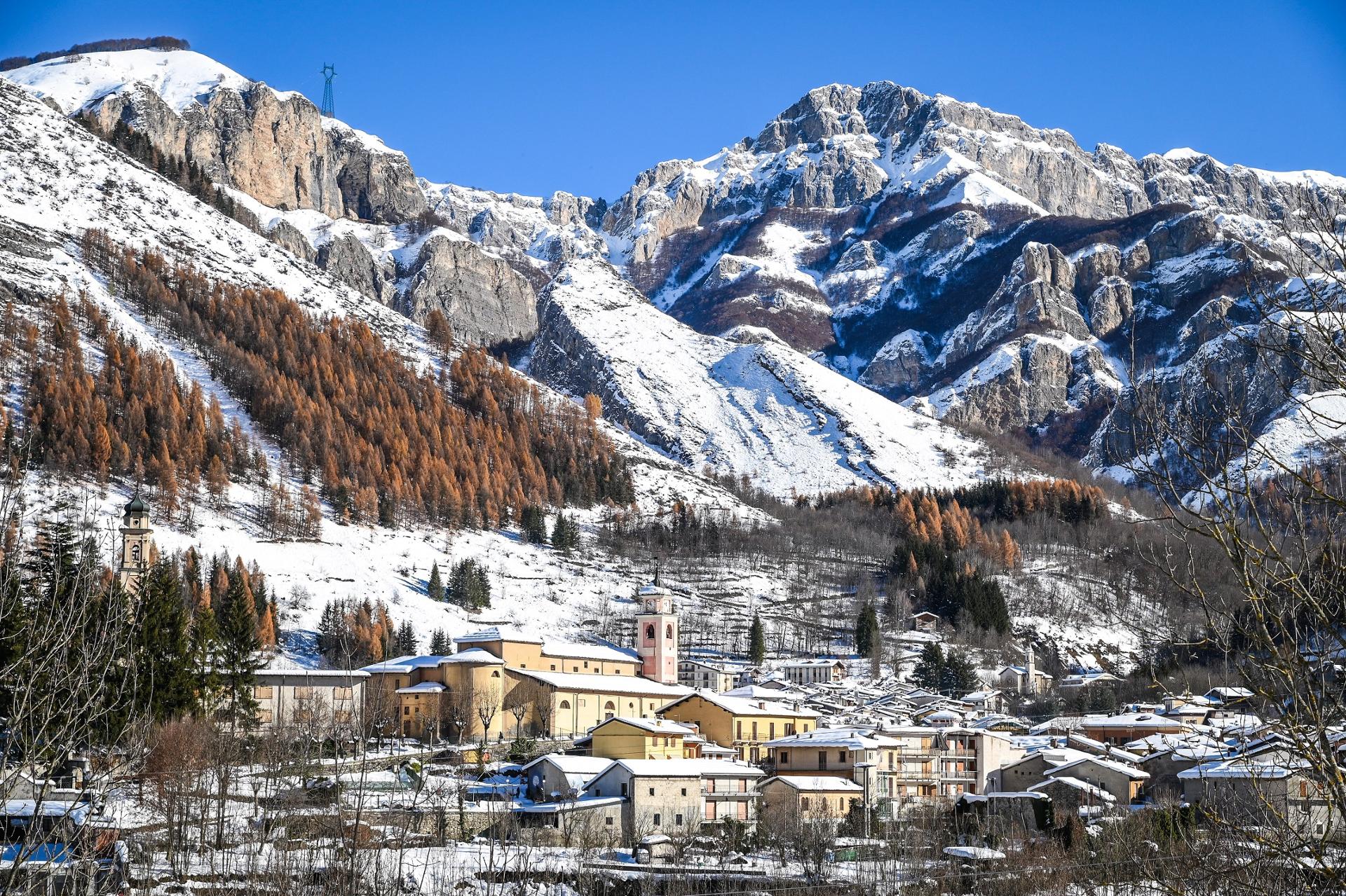A scenic view of the Entracque ski resort in Italy featuring a chalet on the mountainside. The landscape is dotted with winter sports enthusiasts enjoying the snow.