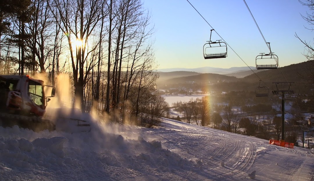 Winter scene in Quechee, Vermont showcasing a bustling ski resort with a ski lift in operation. Skiers can be spotted enjoying the pristine snow-covered slopes amidst a stunning winter landscape.