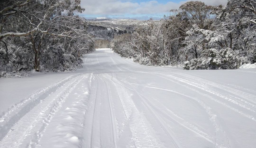 Winter sports scene at Selwyn Snowfields in Kiandra, NSW, Australia, showcasing the winter sports centre, stunning snow-covered landscape, and a chalet.