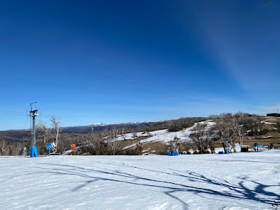 Winter scene at Selwyn Snowfields in Kiandra, Australia. Skiers enjoy the slopes under a bright sky, with a ski lift in the backdrop of this popular ski resort.