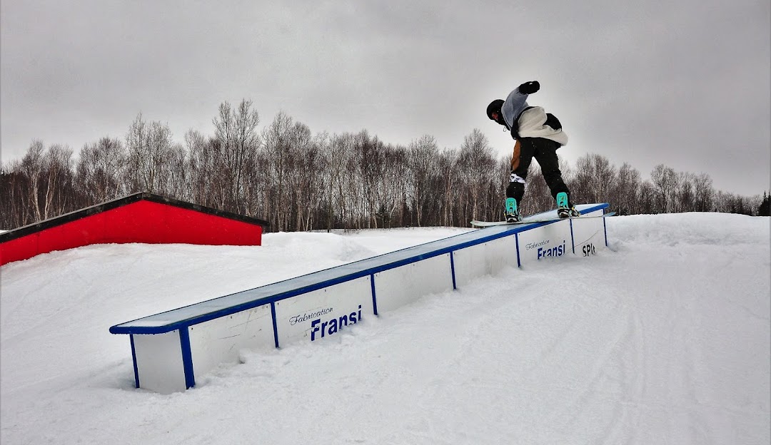 A snowboarder expertly maneuvering down the snowy slopes of Mont Ti-Basse in Baie-Comeau, Quebec, Canada. The scenic winter landscape adds to the exhilarating ride.
