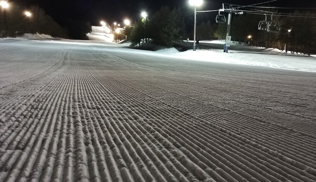 A skier enjoying a winter sport at Mont Ti-Basse ski resort in Baie-Comeau, Quebec, Canada. A chalet and winter sports centre visible in the background of vivid white snowscape.