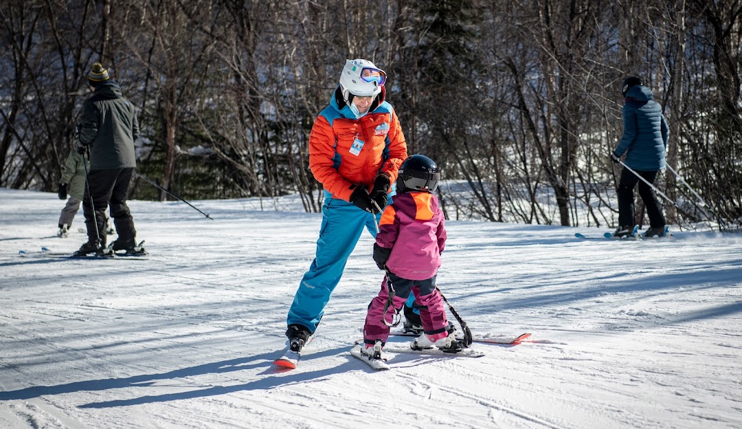 A family and a child are enjoying a day of skiing on Mont Ti-Basse in Baie-Comeau, Quebec, Canada, embodying a lively winter sports scene.