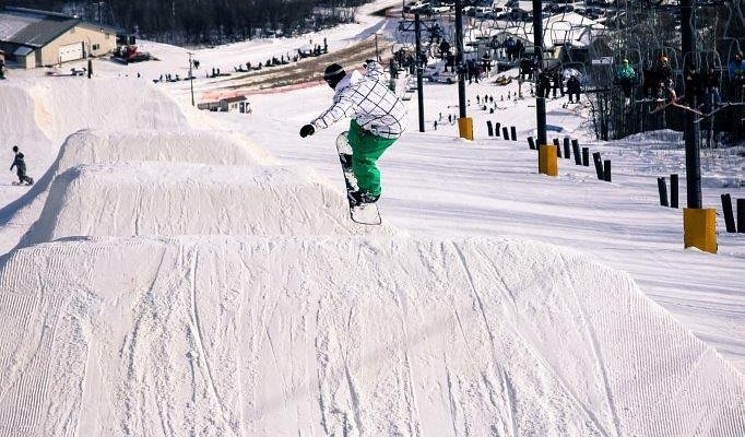 A snowboarder is carving down the slopes at Birch Hill Ski & Snowboard Area in Fort Wainwright Alaska capturing the thrill of winter sports in the scenic Alaskan landscape.