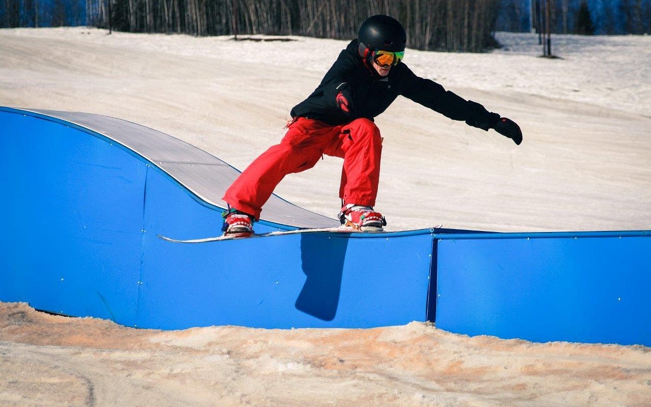 A snowboarder and skier navigate the slopes at Birch Hill Ski & Snowboard Area in Fort Wainwright Alaska a bustling winter sports centre surrounded by a charming chalet.