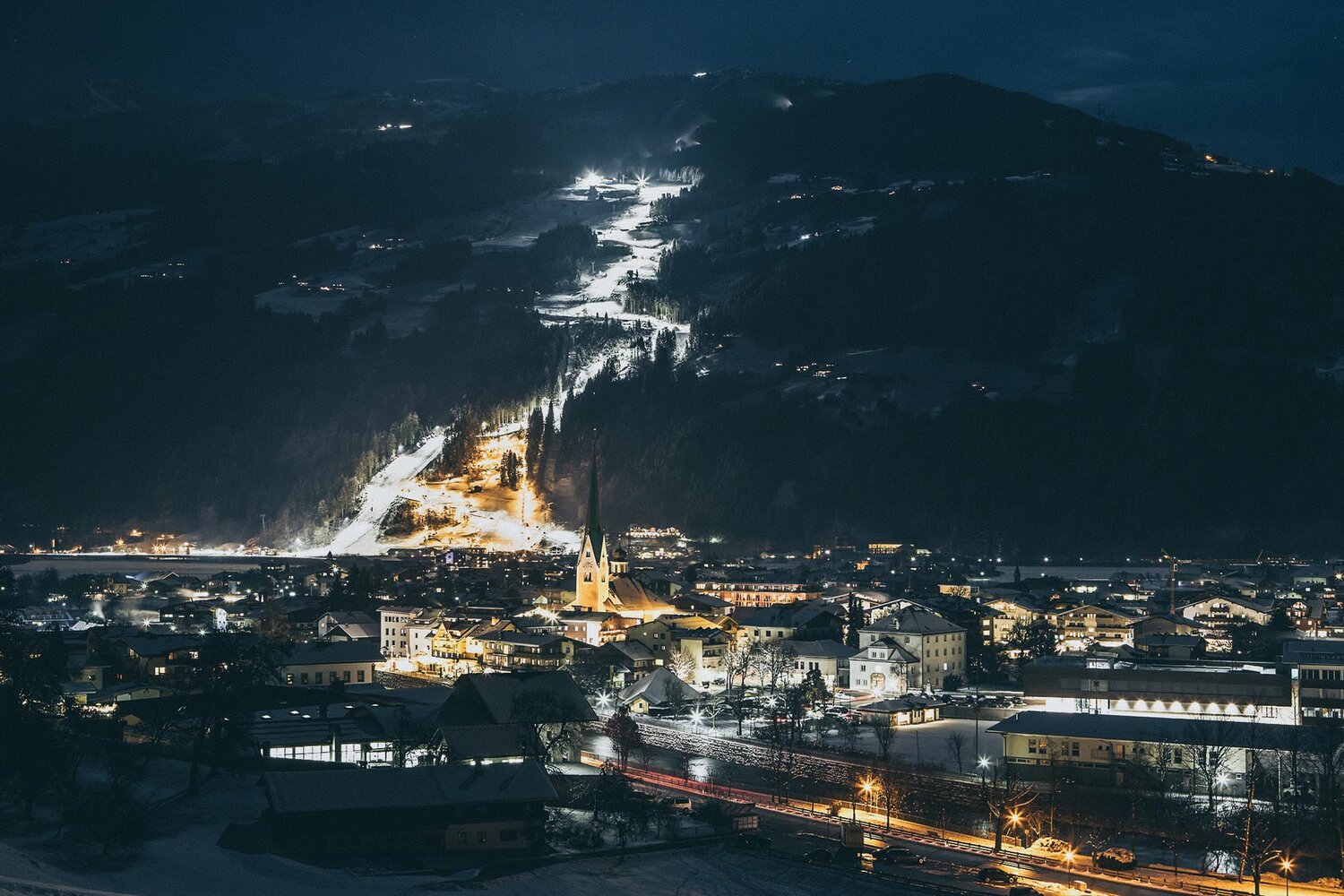 Zillertal Arena – Zell am Ziller | ​Gerlos | ​Königsleiten | ​Hochkrimml in Austria - a view of a town lit up at night.