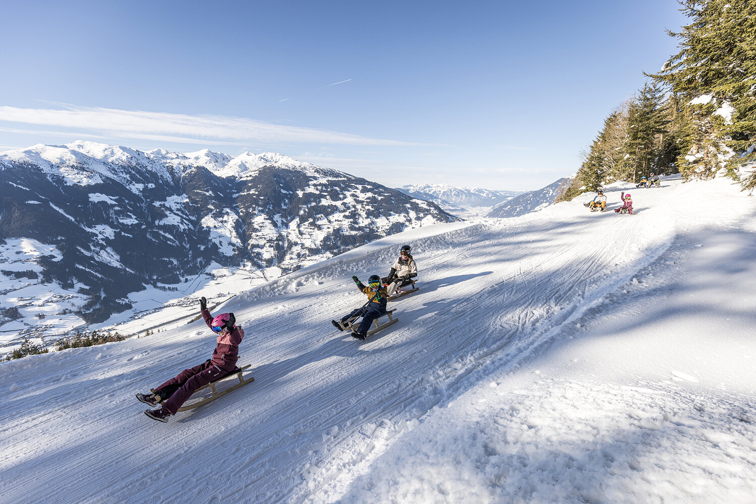 Zillertal Arena – Zell am Ziller | ​Gerlos | ​Königsleiten | ​Hochkrimml in Austria - a group of people riding down a snow covered slope.