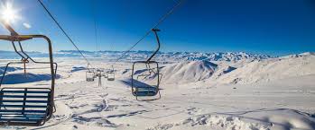 A winter scene at Too Ashuu Ski Base in Kyrgyzstan, featuring a ski lift surrounded by the clean white snow, a cozy challet, skiers enjoying their time, and an overall lively ski resort atmosphere.