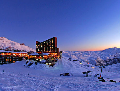 Stunning winter scene at Vallecitos ski resort in Mendoza, Argentina, featuring a chalet and lodge amidst snow-covered slopes.