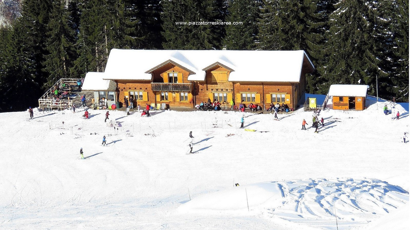 A vibrant winter sports scene at Piazzatorre in Lombardy Italy featuring a bustling ski resort with ski lifts in the background surrounded by beautiful snowy mountains.