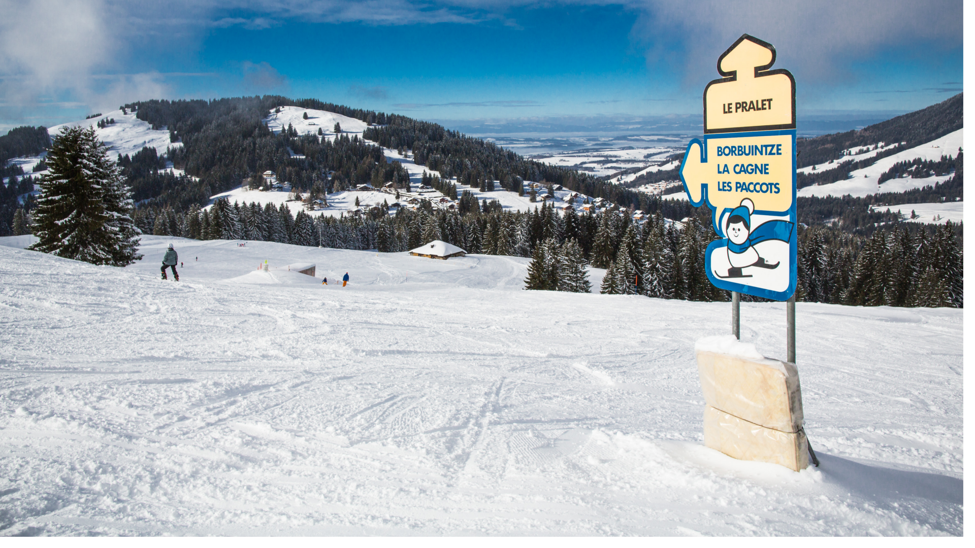 Image showcasing a charming challet nestled in the snowy landscape of Les Paccots in Fribourg, Switzerland. A bustling ski resort adorned with a ski lift and active winter sports enthusiasts can also be seen.