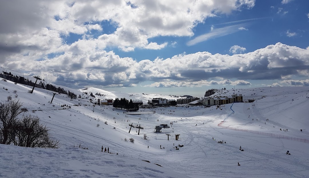 Winter sports in action at Malga San Giorgio in Verona, Italy. The scene features a picturesque chalet amidst a bustling ski resort, set against stunning winter scenery.