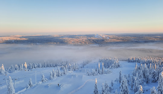 A breathtaking winter scenery in Iso-Syöte Varpuperä showcasing a snow-filled ski resort nestled against a mountain immersed in the calm beauty of Northern Finland.