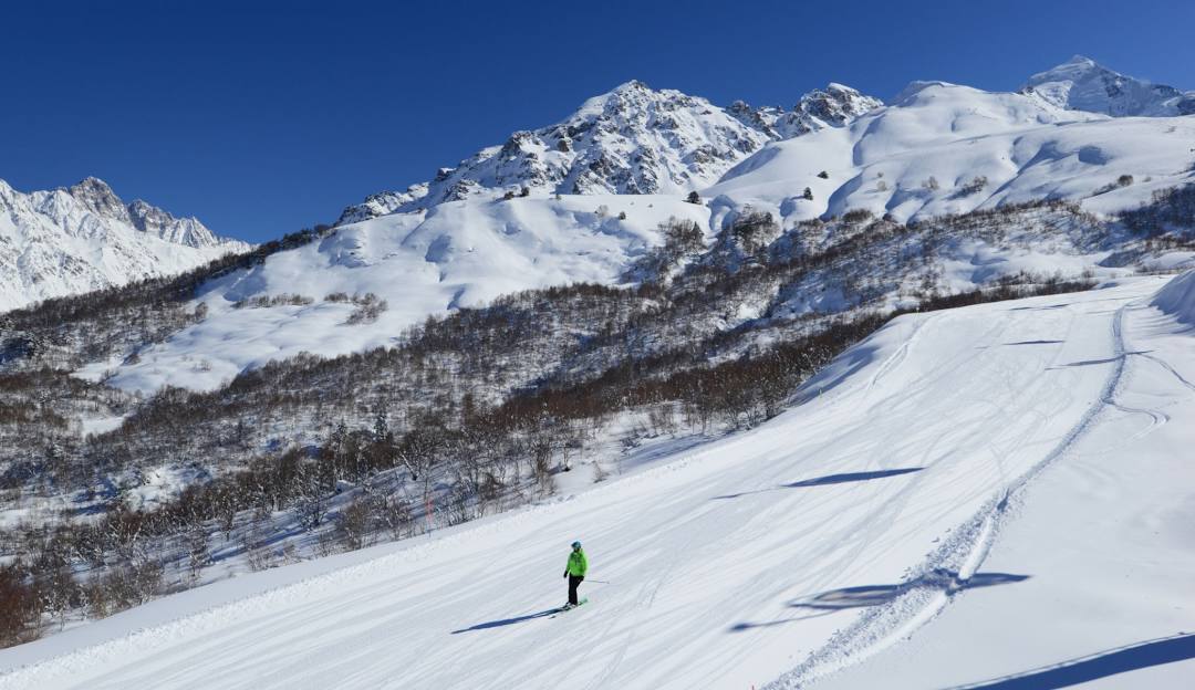 A skier gliding down Perfect North Slopes, a popular ski resort in Lawrenceburg, Indiana. A charming chalet overlooks the winter sports scene, surrounded by captivating winter scenery.