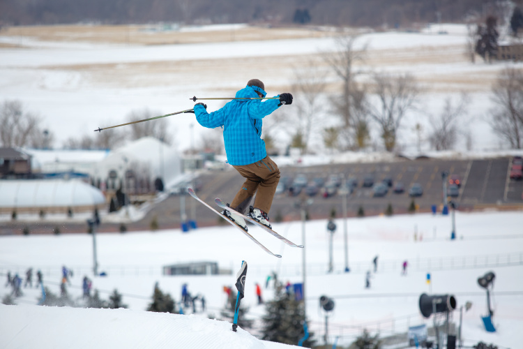 A skier and a snowboarder enjoying the winter sports scene at Perfect North Slopes a ski resort in Lawrenceburg Indiana. A ski lift can be seen in the background.