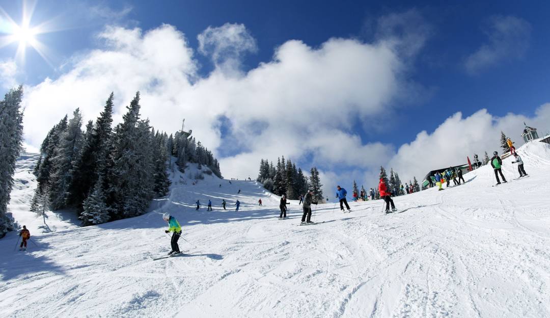 A bustling scene at Perfect North Slopes in Lawrenceburg Indiana showing skiers enjoying the winter sport a ski lift transporting attendees surrounded by a ski resort with a cozy chalet in the background.