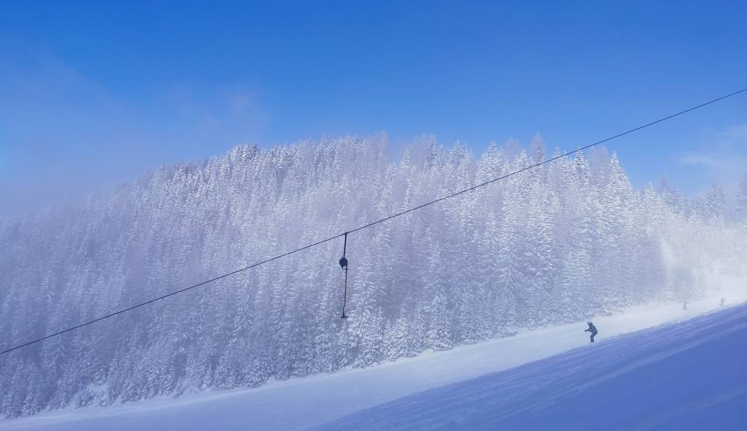 A skier gliding down the snow-covered slopes at Perfect North Ski Resort in Lawrenceburg, Indiana with a ski lift nearby, set amid a beautiful, wintry landscape.