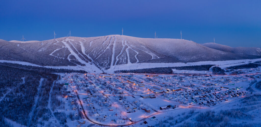 Ski resort at Mont Miller in Murdochville, Quebec with snow-covered slopes amidst stunning winter scenery, featuring a chalet and winter sports activities.