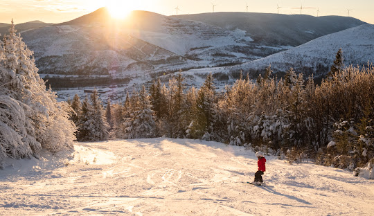A winter sports scene at Mont Miller with a skier and a family skiing in the breathtaking winter scenery of Murdochville, Quebec, Canada.