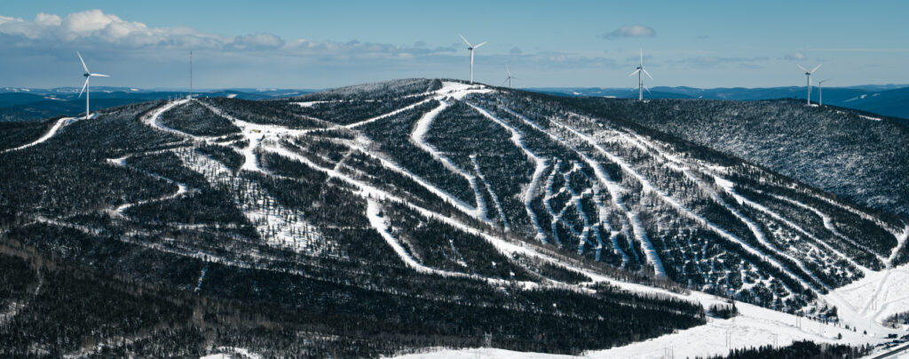 A skier enjoys a winter day at the Mont Miller ski resort in Quebec Canada. Ski lifts ascend the snow-covered slopes contributing to a lively winter sports scene.