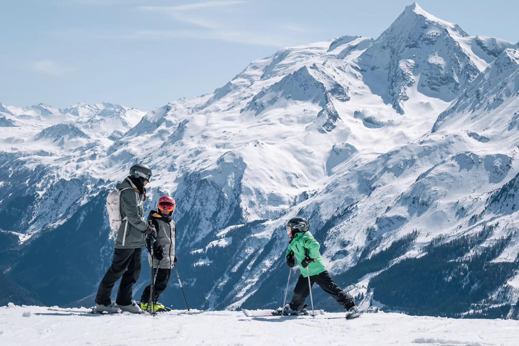 A family engaging in winter sports at the Ruine Super Saint-Bernard ski resort in Switzerland surrounded by the snowy landscape.
