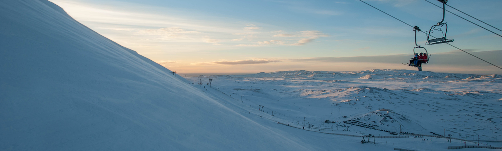 View of the bustling Skálafell ski resort in Greater Reykjavik, Iceland, featuring snow-covered slopes, a ski lift, and winter sports activities in progress.