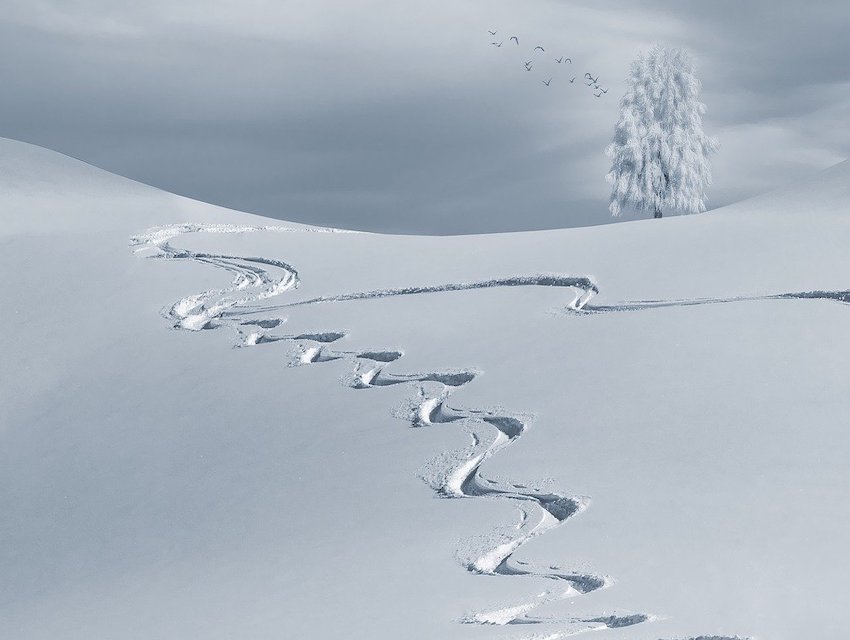 Winter sports scene in Skálafell, Iceland with a picturesque winter view as a backdrop. Visible elements include a skier and a cozy chalet amidst the snow-covered landscape.