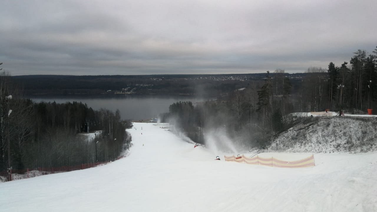 A snowy scene at Krasnoye Ozero, a popular ski resort in Northwest Russia. Skiers enjoy the slopes, aided by a ski lift, amidst a picturesque winter landscape.