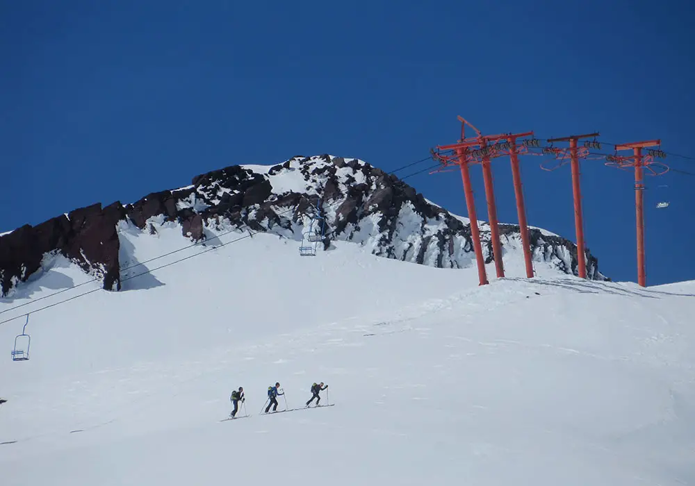 A winter sports scene at Vulcan Pass Romania featuring a mountain backdrop a ski resort a moving ski lift and a skier skillfully navigating the snow-covered slopes.