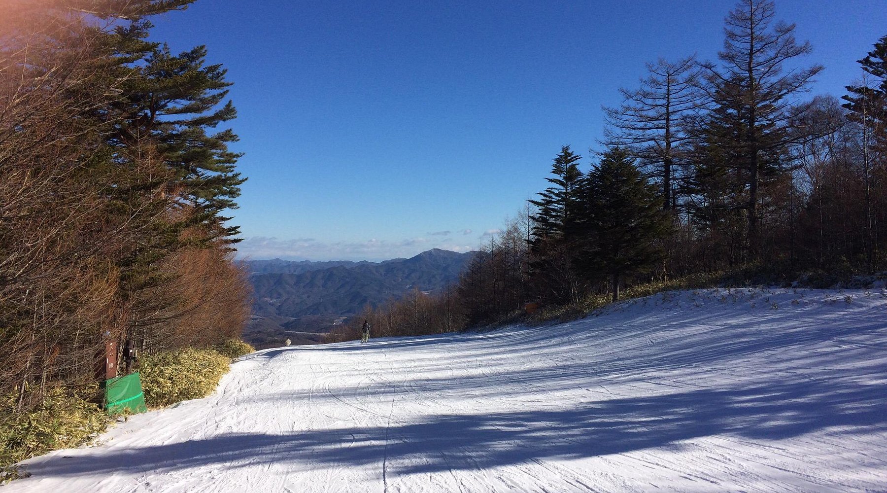 Winter sports scene at Chateraise Ski Valley Koumi, featuring a skier on a snowy slope and a chalet nestled amidst stunning winter scenery in Nagano, Japan.