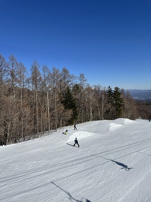A skier in action at Chateraise Ski Valley Koumi, amidst a winter sports scene. Features include a ski resort with a charming challet and ski lift in Nagano, Japan.