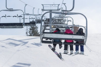 A winter scene at Brimacombe ski resort in Orono Ontario Canada featuring a ski lift and people enjoying various winter sports activities.