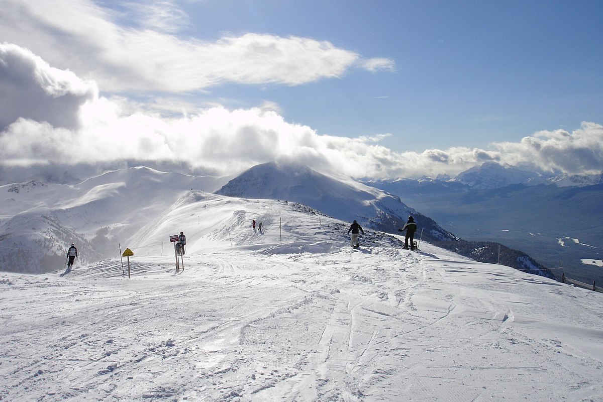 Whispering Pines in Canada - a group of people skiing down a snowy mountain.