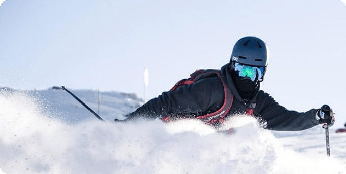 A skier in action at Peyragudes, Hautes-Pyrénées, Occitanie, France. The winter sports scene is set against a backdrop of a chalet and snowboarders are also present.