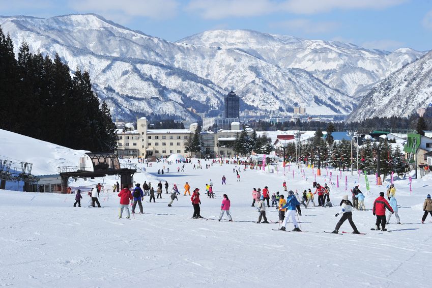 Yuzawa Park in Japan - a group of people skiing down a snow covered slope.