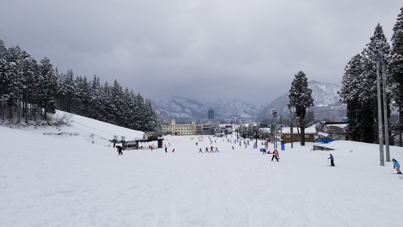 Yuzawa Park in Japan - a group of people skiing down a snow covered slope.