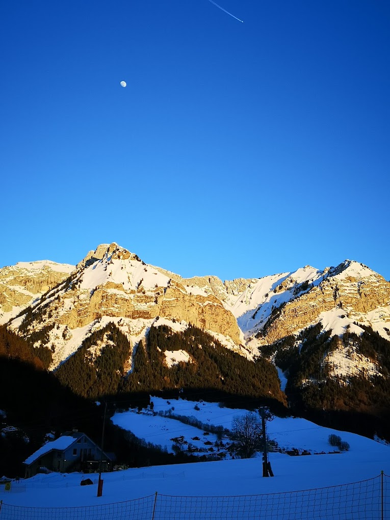 La Forclaz in Switzerland - a view of a mountain range with a moon in the sky.