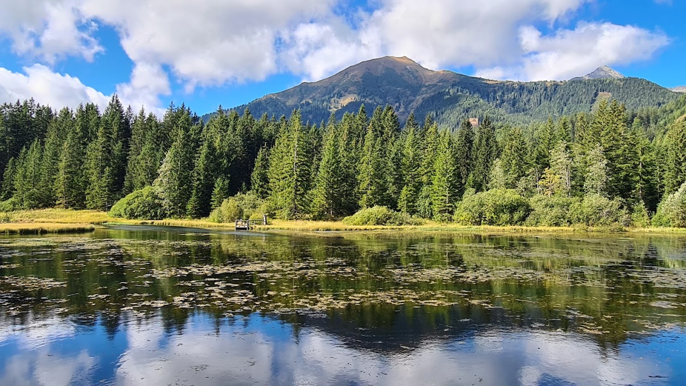 Hohentauern in Austria - a body of water surrounded by trees and mountains.
