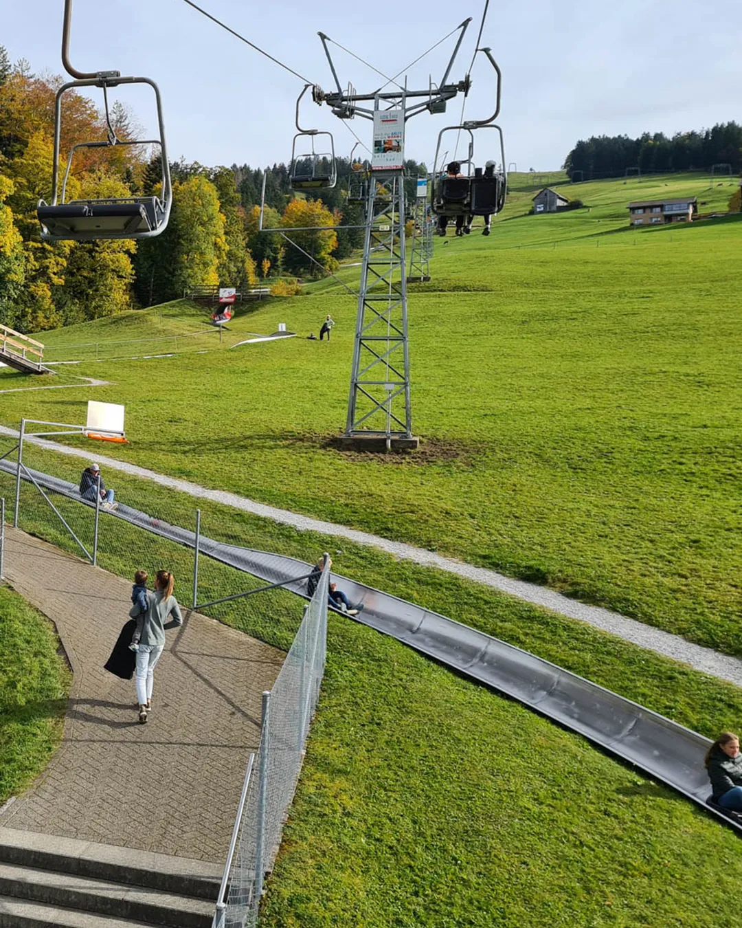 Atzmännig in Switzerland - people sitting on the grass in front of a ski lift.