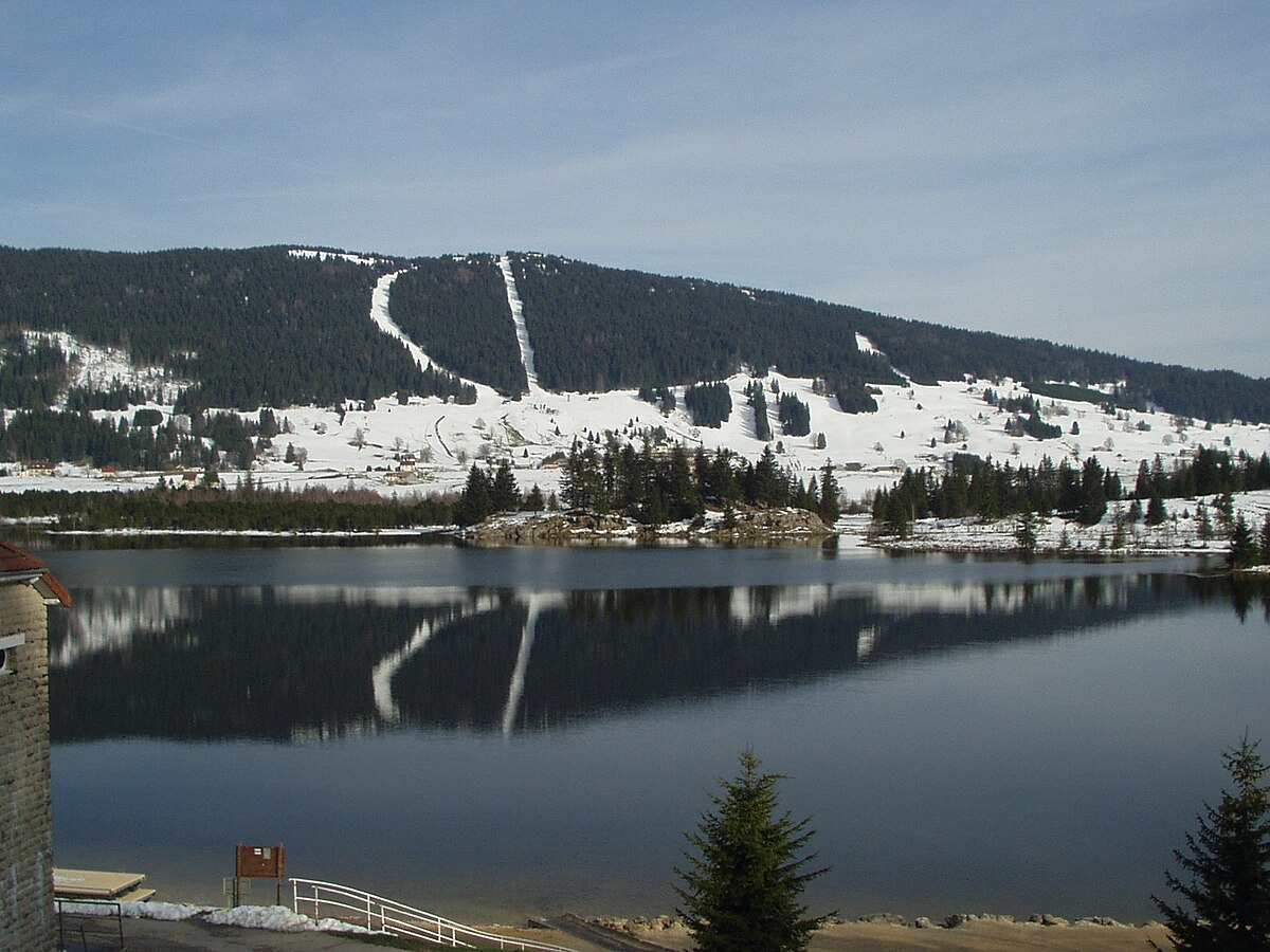 Le Noirmont in France - a lake in the mountains with snow on it.
