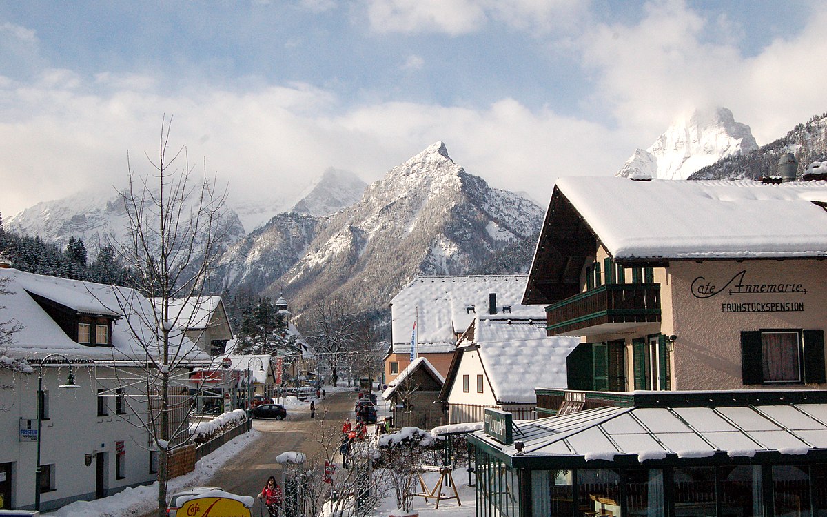 Hinterstoder – Höss in Austria: a street with snow covered buildings and mountains in the background.