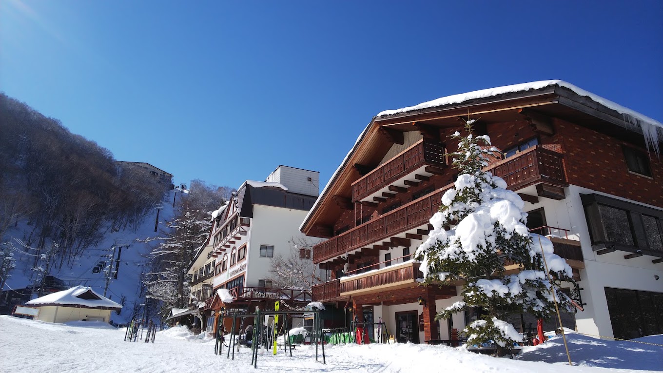 Giant Ski area in Japan: a snow covered ski slope with a building in the background.