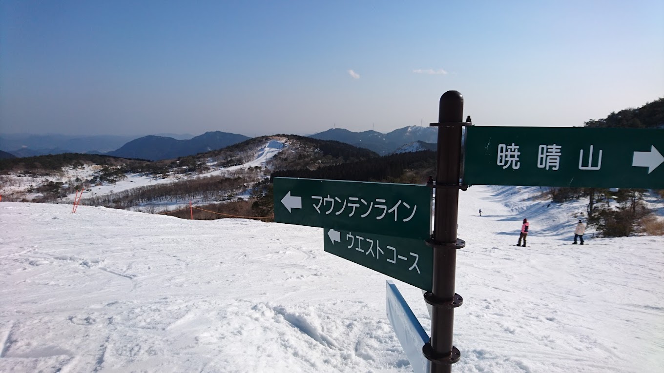 Mineyama Kogen in Japan - a green sign on top of a snow covered mountain.