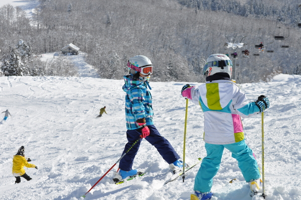 Asahi Shizen in Japan - a group of children skiing down a snowy hill.