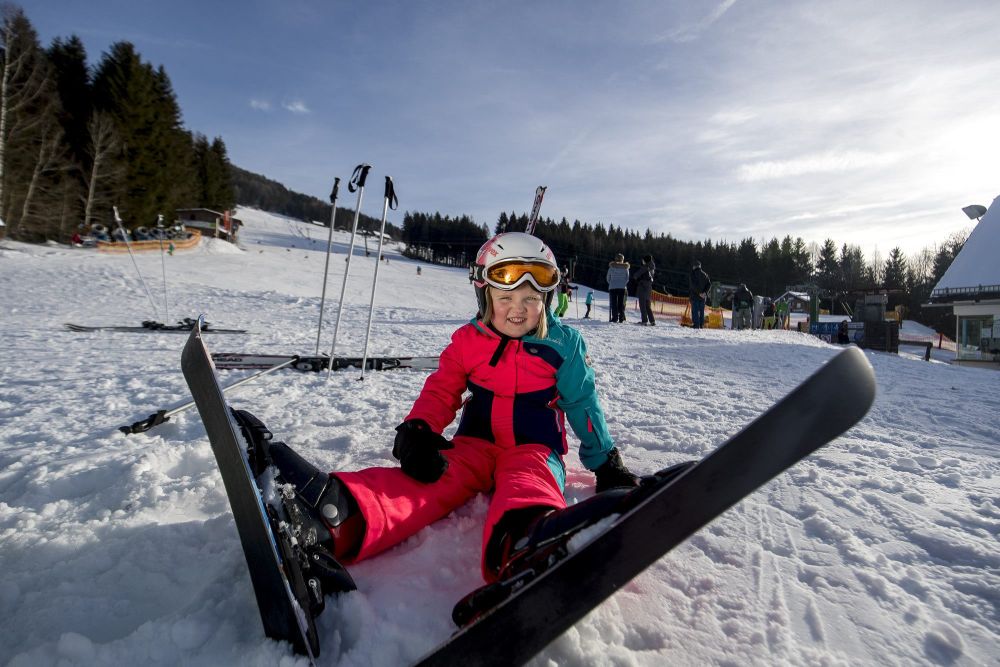 Schwabenbergarena Turnauer Schilift in Austria - a young girl sits in the snow on her ski board.