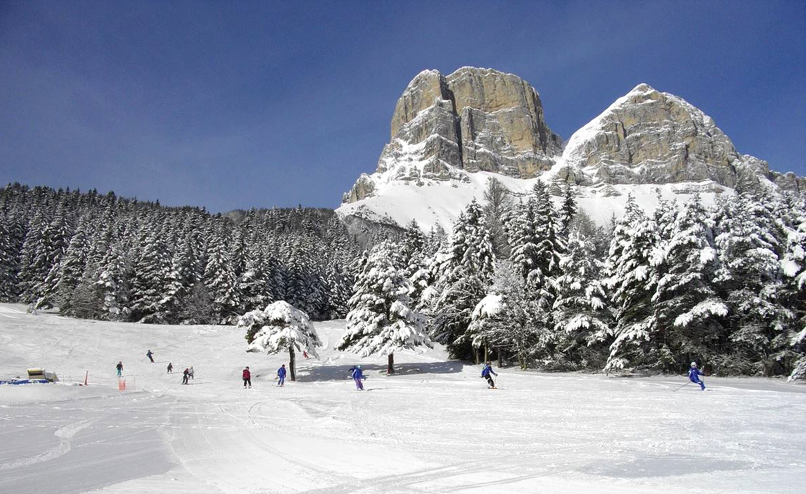 Col de l'Arzelier in France - a group of people skiing down a snow covered slope.