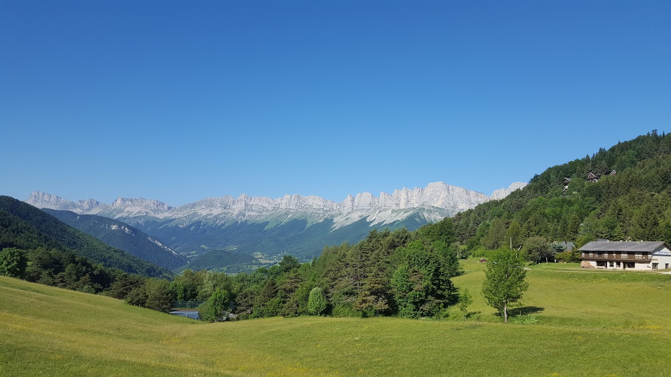 Col de l'Arzelier in France - a green field with mountains in the background.